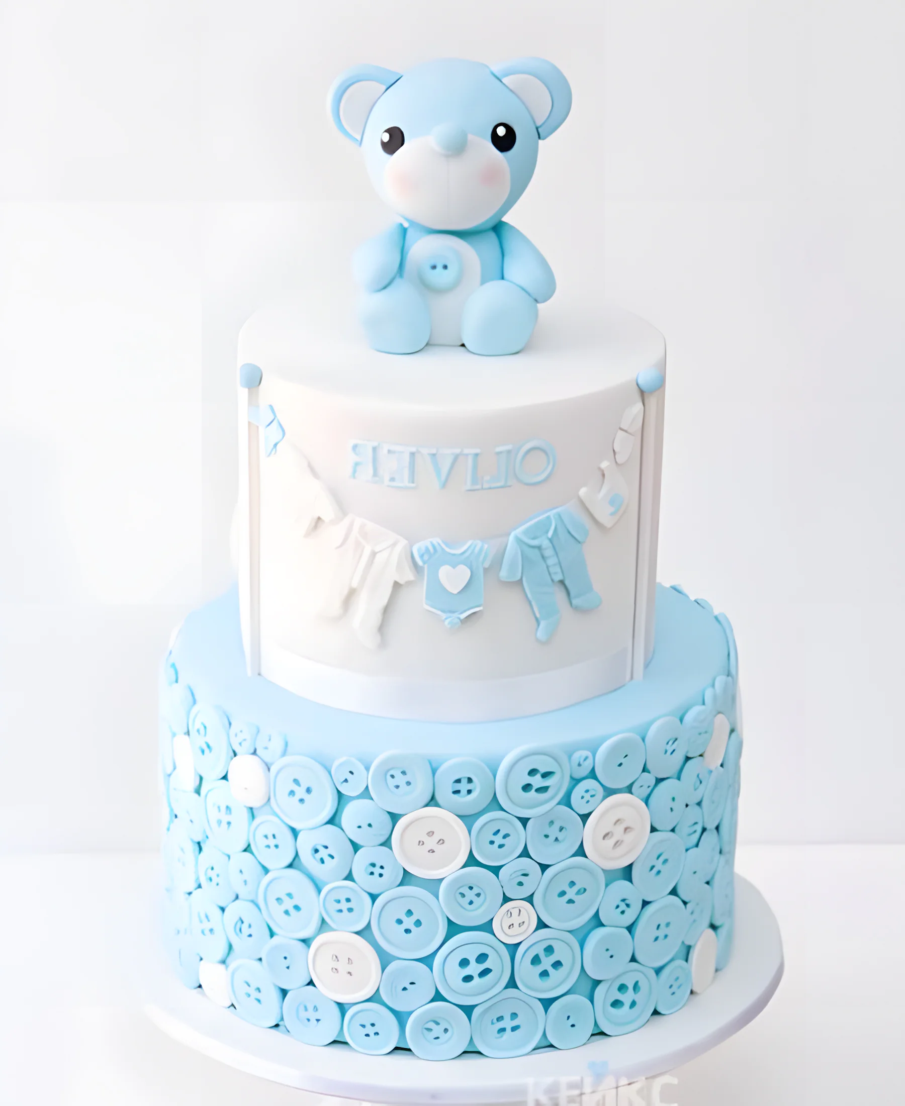 Белый торт с голубыми пуговицами и медведем Фото