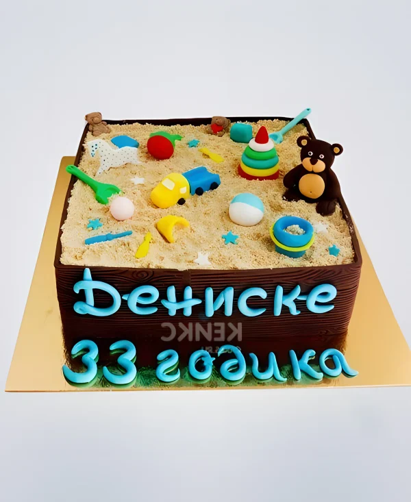 Торт с игрушками в песке и голубой надписью Фото